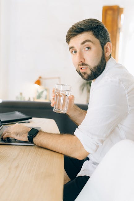 Man stretching his shoulders while working remotely at a desk